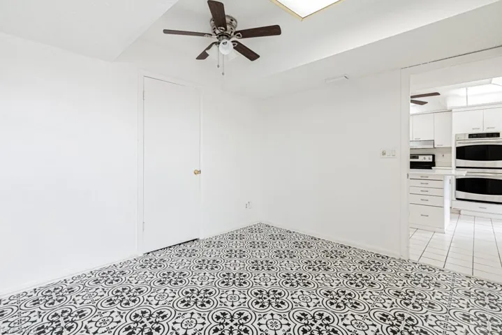 Empty room featuring light tile flooring and ceiling fan