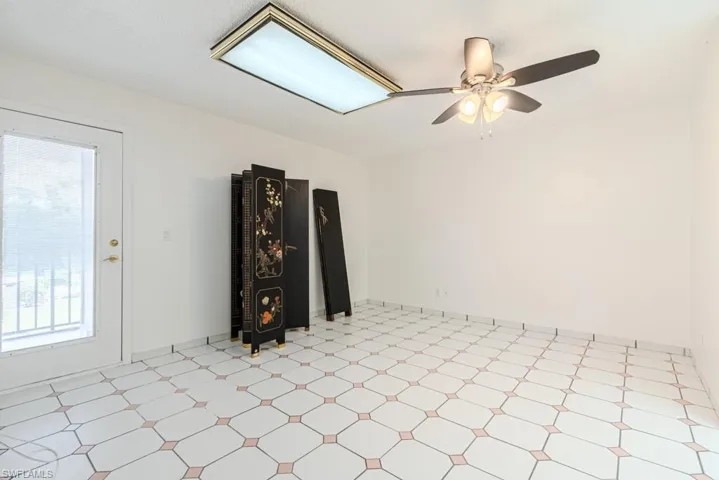 Tiled spare room featuring a wealth of natural light and ceiling fan