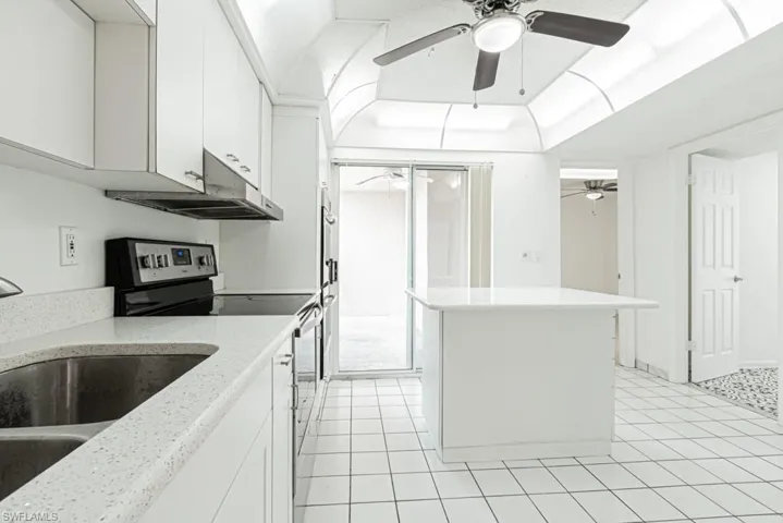 Kitchen with ceiling fan, stainless steel range oven, light tile floors, sink, and white cabinetry