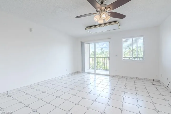 Unfurnished room with a textured ceiling, light tile flooring, and ceiling fan