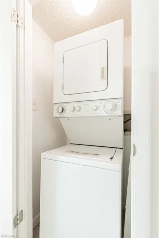 Laundry area featuring stacked washing maching and dryer and a textured ceiling