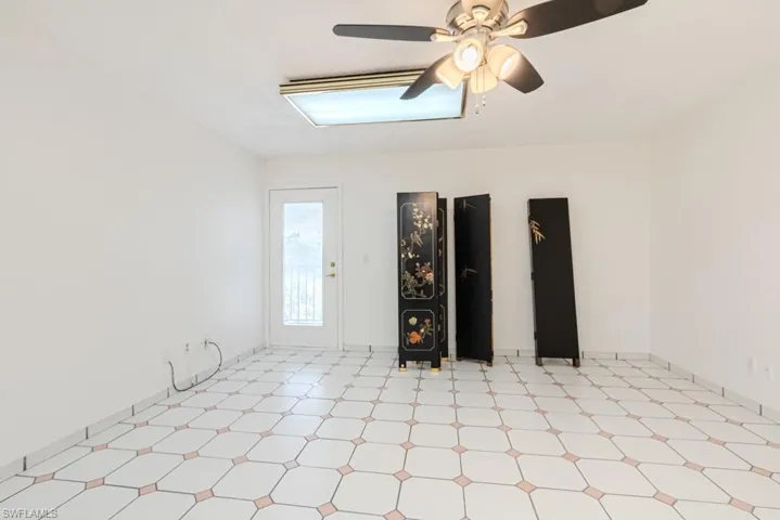 Unfurnished living room featuring ceiling fan and light tile flooring