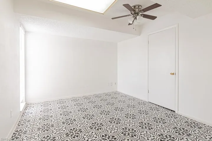 Tiled empty room featuring a textured ceiling and ceiling fan