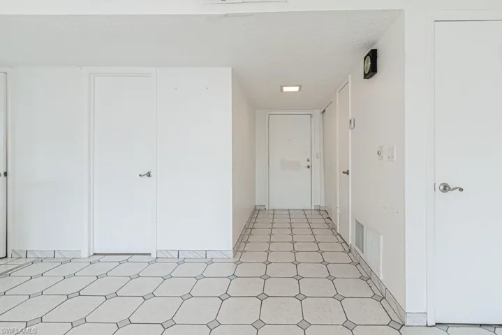 Hall featuring light tile floors and a textured ceiling