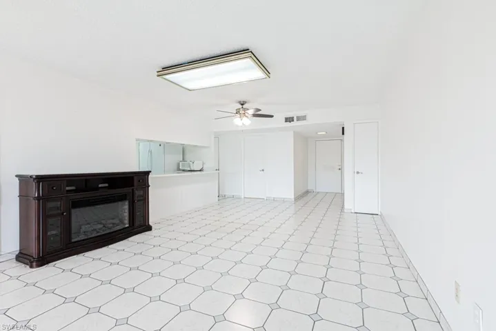 Unfurnished living room featuring ceiling fan and light tile flooring