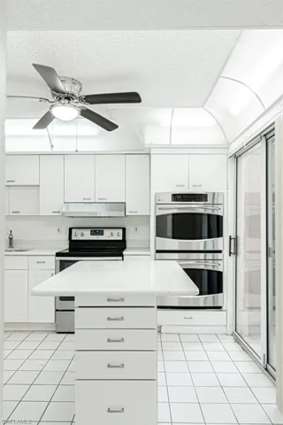 Kitchen featuring stainless steel appliances, ceiling fan, white cabinetry, sink, and light tile floors