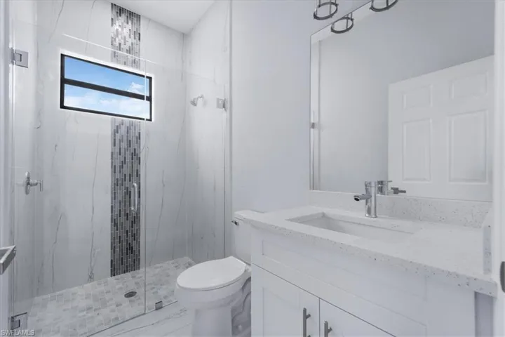 Bathroom featuring vanity, walk in shower, and toilet