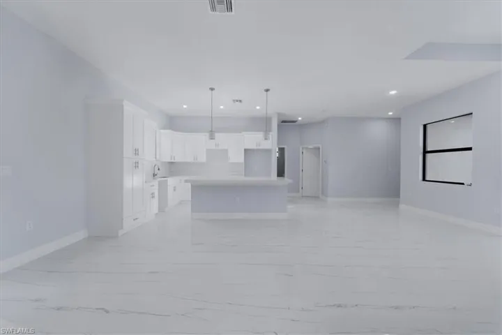 Kitchen with sink, a center island, decorative light fixtures, and white cabinets