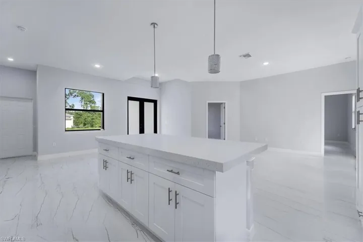 Kitchen with white cabinetry, a center island, and pendant lighting