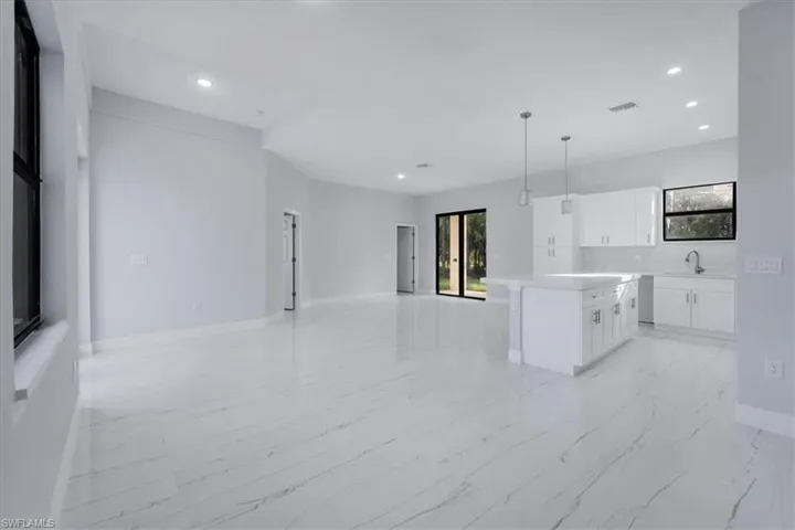 Kitchen with white cabinets, a center island, hanging light fixtures, and sink