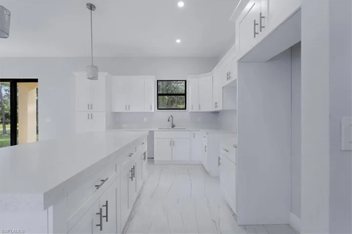 Kitchen with sink, white cabinetry, a center island, and hanging light fixtures