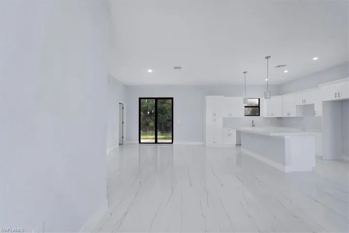 Kitchen with white cabinetry, a kitchen island, and hanging light fixtures