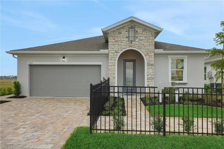 View of front of house with stucco siding, stone siding, a fenced front yard, decorative driveway, and roof with shingles