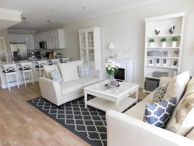 Living area with crown molding, light wood-type flooring, and a fireplace
