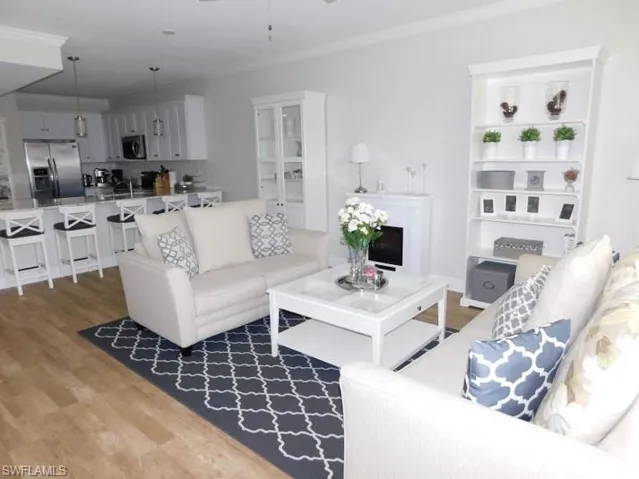 Living room featuring ornamental molding, wood finished floors, a ceiling fan, and a fireplace