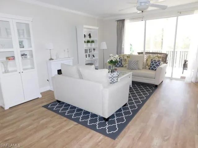 Living room featuring light wood-style flooring, ceiling fan, and crown molding