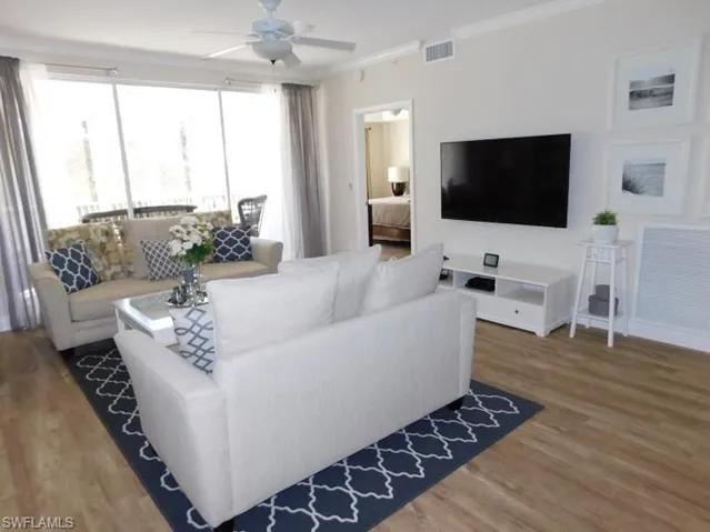 Living area featuring a ceiling fan, wood finished floors, and ornamental molding