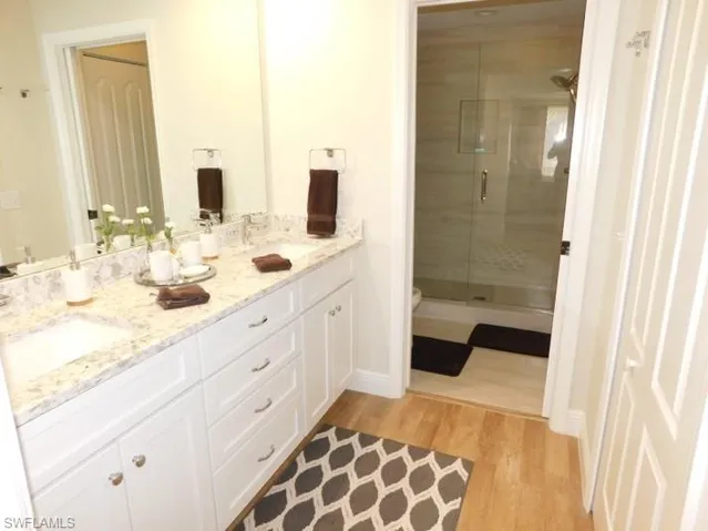 Full bathroom with wood finished floors, double vanity, and a stall shower