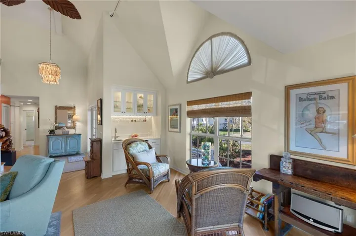 Living room featuring an inviting chandelier, high vaulted ceiling, and light wood-type flooring