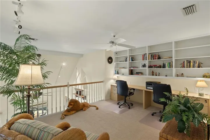 Carpeted home office featuring ceiling fan