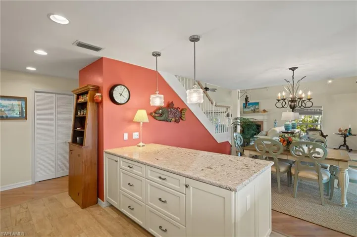 Kitchen with white cabinetry, light stone counters, light hardwood / wood-style floors, and decorative light fixtures