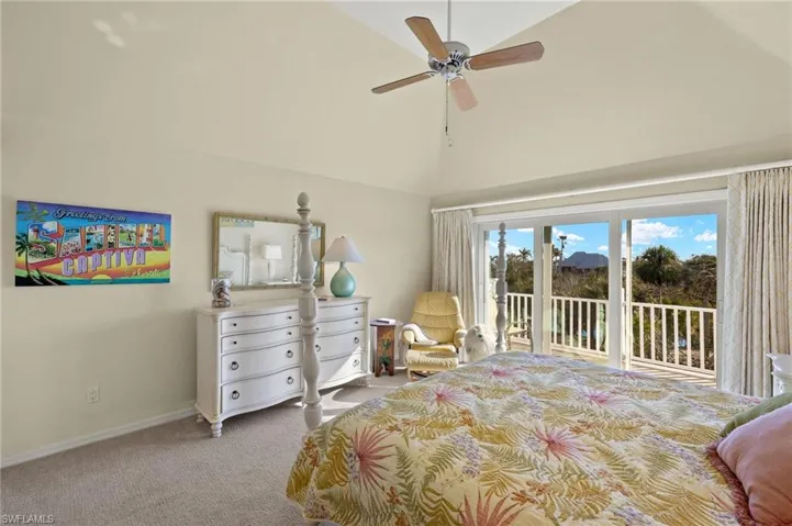 Carpeted bedroom featuring ceiling fan, high vaulted ceiling, and access to outside