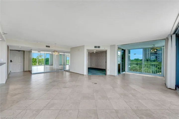 Unfurnished living room featuring ceiling fan and a chandelier