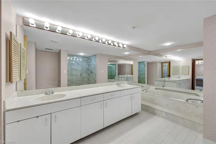 Primary bathroom with a marble finish shower, double vanity, light tile patterned flooring, and a bath