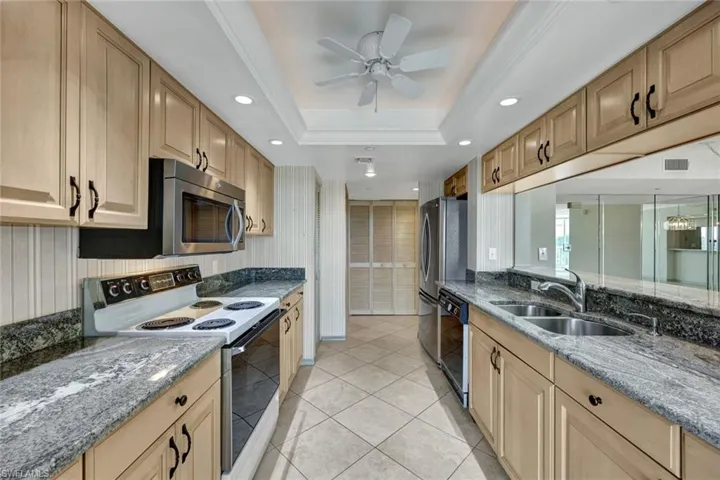 Kitchen featuring range with electric cooktop, dark stone counters, recessed lighting, light tile patterned floors, and black dishwasher