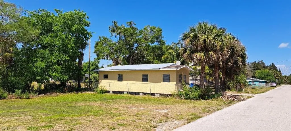 View of property exterior with a yard, fence, and stucco siding