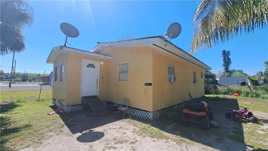 View of side of home with stucco siding, entry steps, crawl space, fence, and cooling unit
