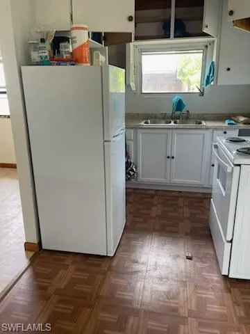 Kitchen featuring white appliances, white cabinets, and light countertops
