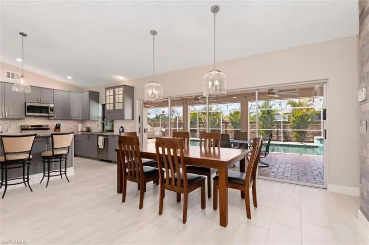 Dining space with ceiling fan with notable chandelier, vaulted ceiling, and visible vents