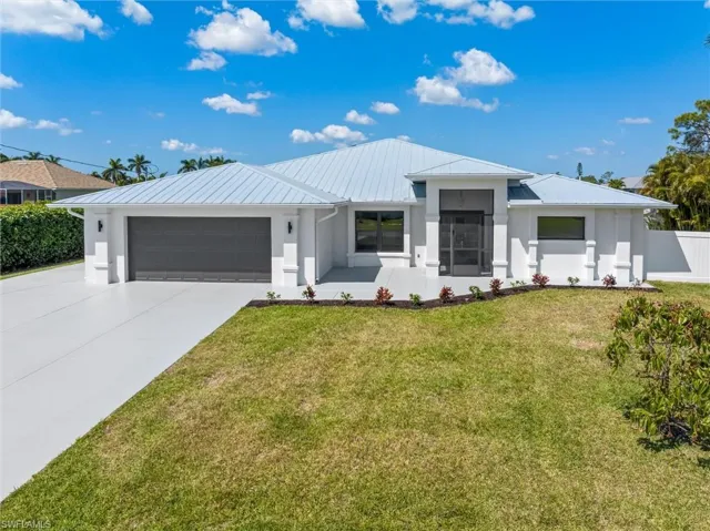 View of front of property featuring concrete driveway, stucco siding, fence, a front lawn, and a garage