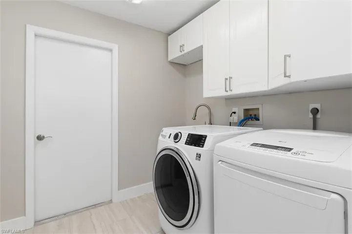 Clothes washing area with baseboards, separate washer and dryer, and cabinet space
