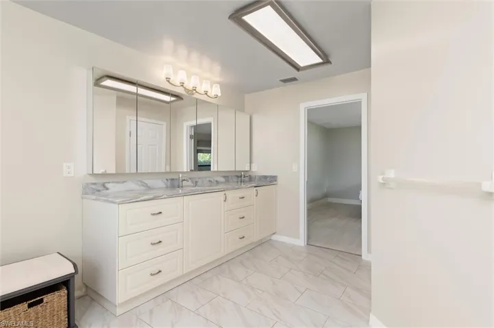 Primary Full bathroom featuring baseboards, marble finish floor, visible vents, and double vanity