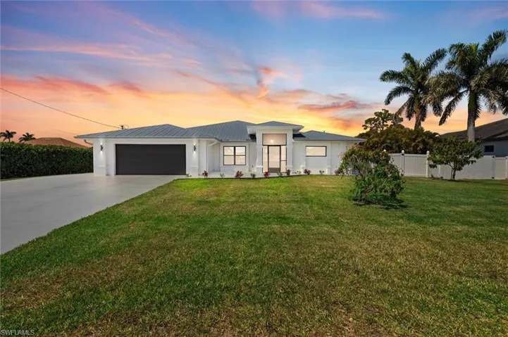 View of front of property featuring driveway, a garage, fence, and a front yard
