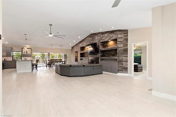 Living area featuring a fireplace, ceiling fan, baseboards, and vaulted ceiling