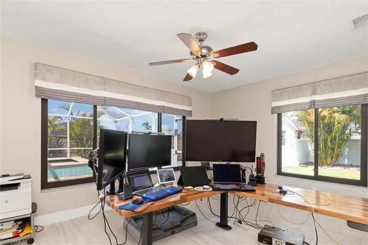 Bedroom/Office space featuring baseboards, visible vents, wood finished floors, and a ceiling fan