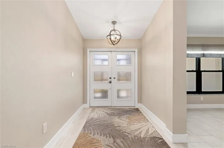 Doorway to outside with baseboards and a chandelier