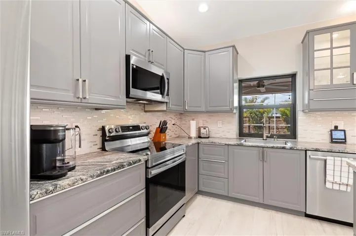 Kitchen featuring a sink, stainless steel appliances, gray cabinetry, and decorative backsplash