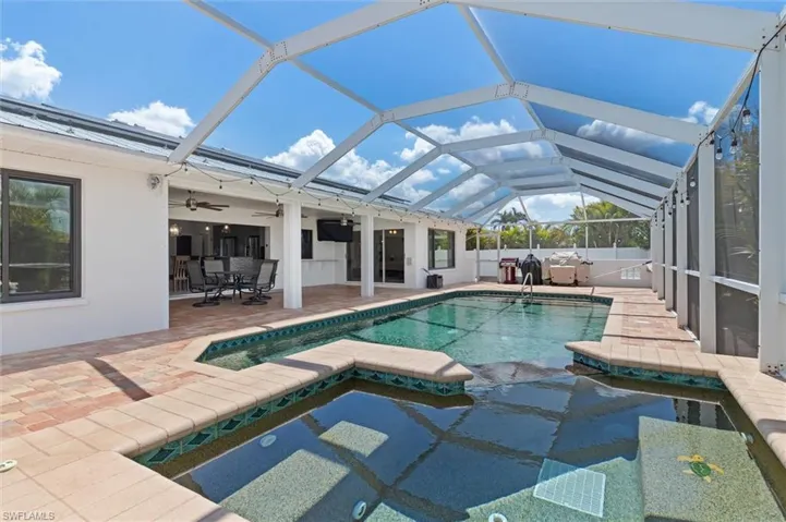 View of swimming pool/spa featuring a ceiling fan, a pool with connected hot tub, a lanai, and a patio area