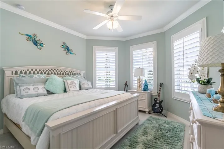 Bedroom with multiple windows, ceiling fan, and ornamental molding