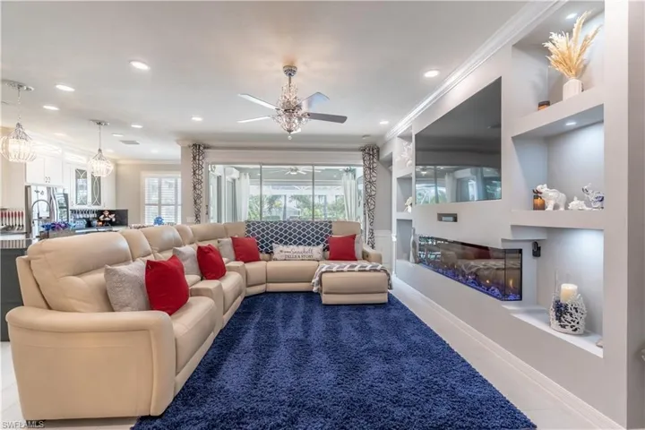Living room with built in features, ceiling fan, and ornamental molding