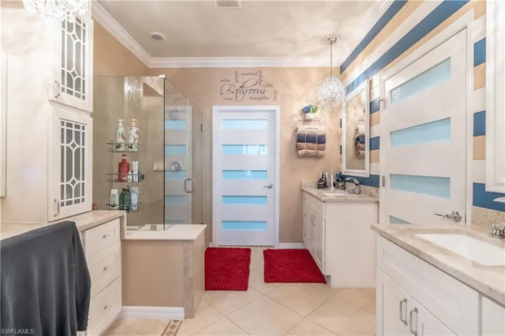 Bathroom with double vanity, tile patterned flooring, a shower with door, and ornamental molding