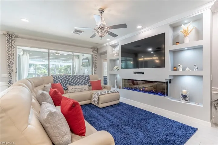 Living room featuring built in shelves, ornamental molding, and ceiling fan