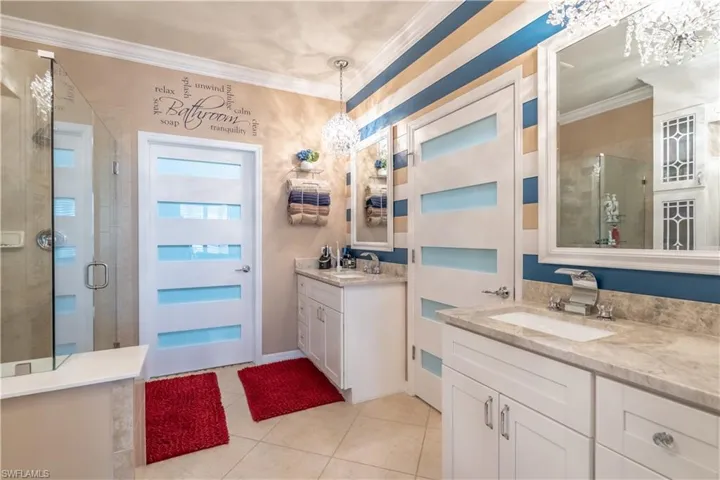 Bathroom with an enclosed shower, crown molding, tile patterned flooring, and dual bowl vanity