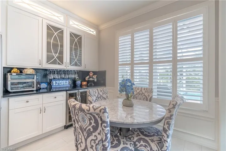Dining room featuring beverage cooler, crown molding, and light tile patterned floors