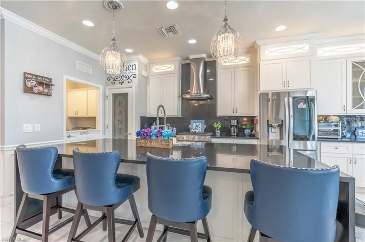 Kitchen with appliances with stainless steel finishes, decorative backsplash, wall chimney range hood, and a kitchen island