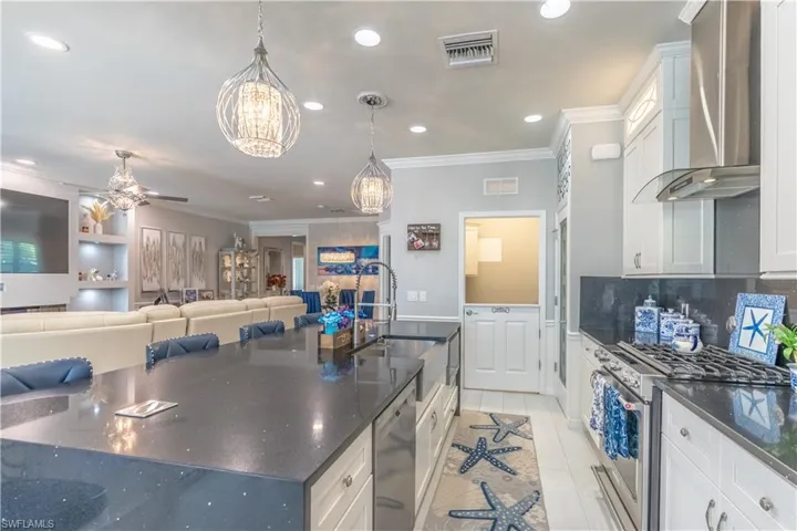 Kitchen featuring wall chimney range hood, sink, white cabinetry, and stainless steel appliances